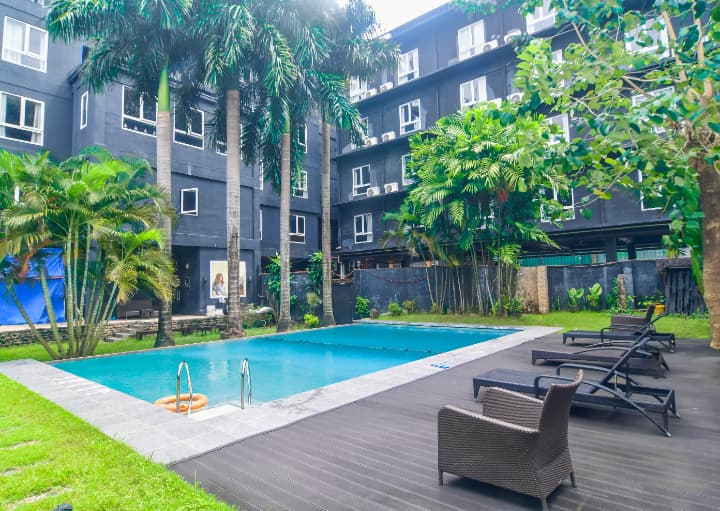 CELLAプレミアム校内にある屋外スイミングプール。周囲にはヤシの木とリクライニングチェアが並び、リゾート感のある落ち着いた雰囲気の中でリラックスできる空間