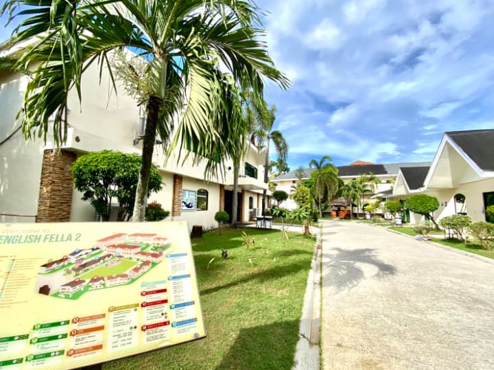 English Fella 2のキャンパス内通路と校舎の外観。南国の植物と案内板が設置されており、広々とした清潔な環境が印象的。