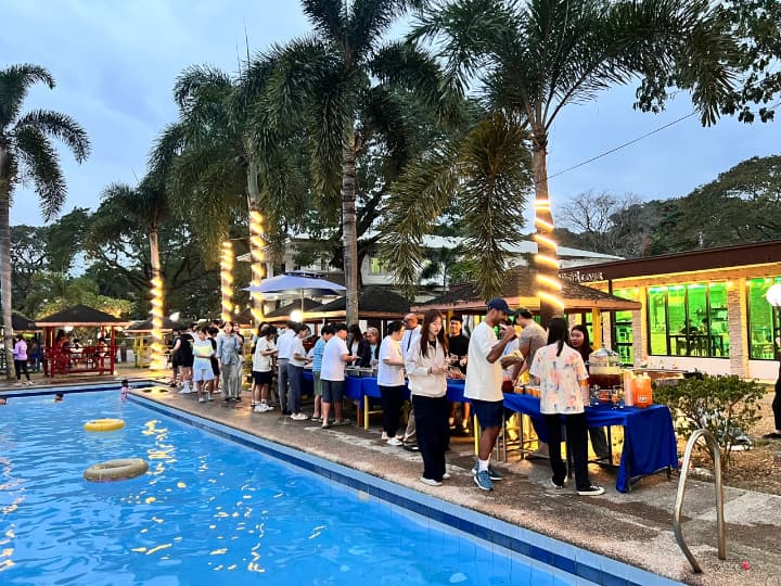 プールサイドパーティーで、ビュッフェの列に並ぶ人々。