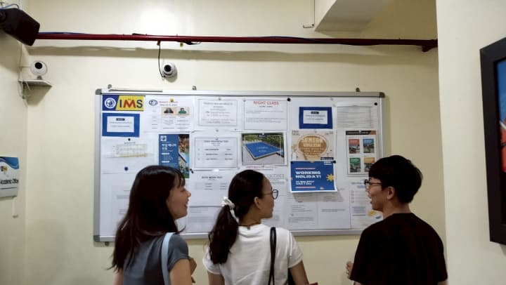 フィリピン留学学校の掲示板を見る生徒3人