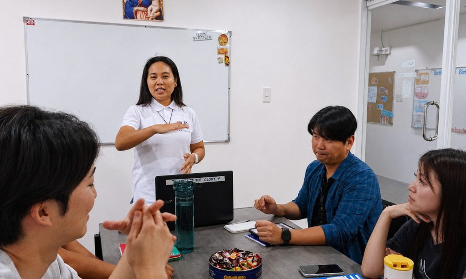 3D Academyのグループ授業。ホワイトボードの前で講師が説明し、留学生2人が聞いている