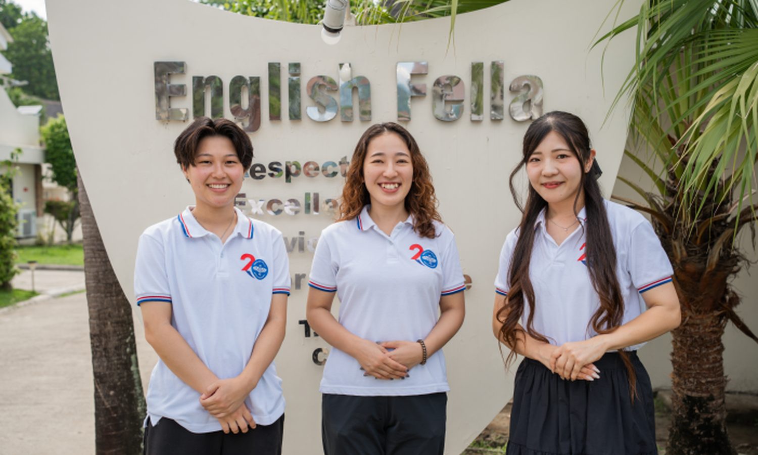 English Fella 1・2の日本人スタッフ。学校の看板の前で3人が並ぶ
