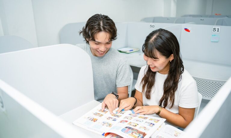 English Fella 1の自習室。仕切りのある席で留学生2人が教科書を開いている