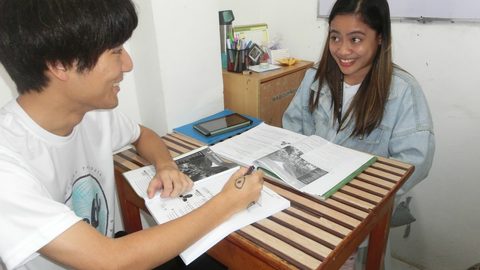 English Fella 2のマンツーマン授業。講師と留学生が教材を見ながら話している