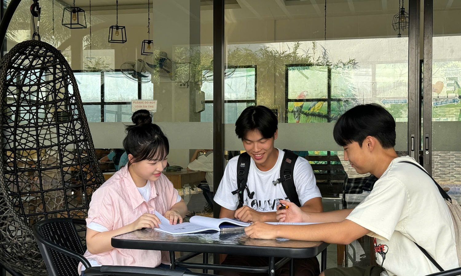 I.BREEZE メイン校のテラスで教科書を広げて勉強する留学生3人