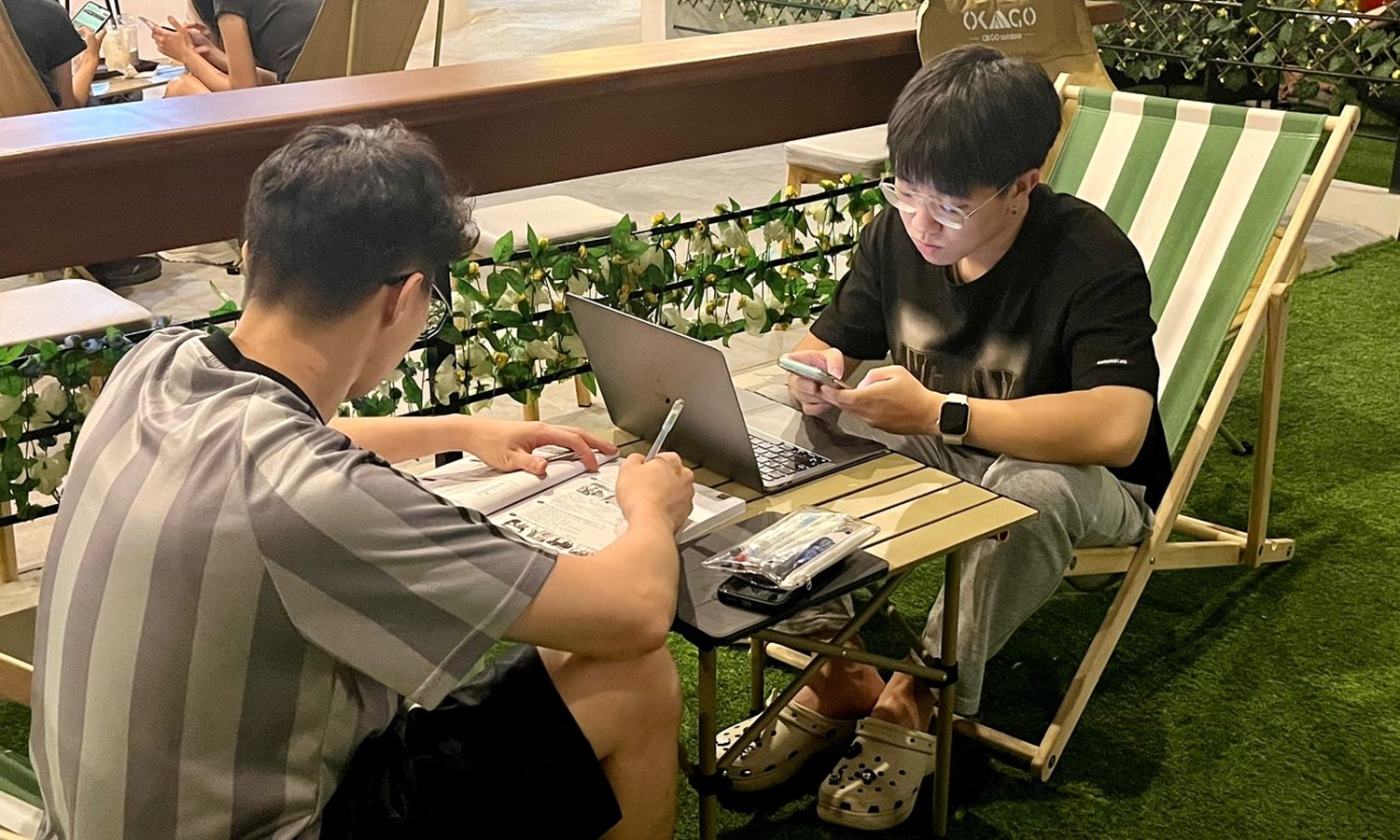 I.BREEZE プライム校のBreeze Cafeでキャンプチェアに座って勉強する学生