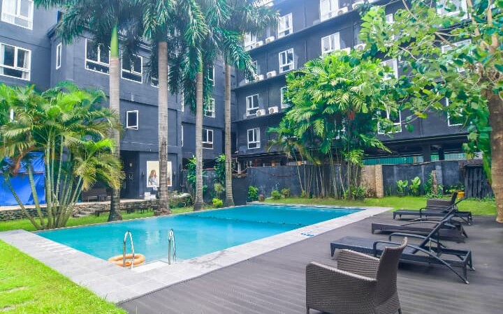 CELLAプレミアム校内にある屋外スイミングプール。周囲にはヤシの木とリクライニングチェアが並び、リゾート感のある落ち着いた雰囲気の中でリラックスできる空間