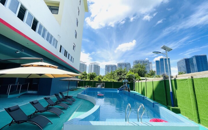 B'Cebuの屋外プールとサンベッド。奥にキャンパスの建物