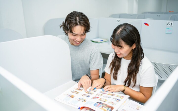 English Fella 1の自習室。仕切りのある席で留学生2人が教科書を開いている