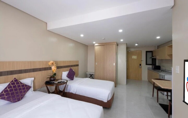 I.BREEZE の外部寮コンドミニアム（Cebu Family Suites）の寝室。ホテルのようなベッドとテレビがある
